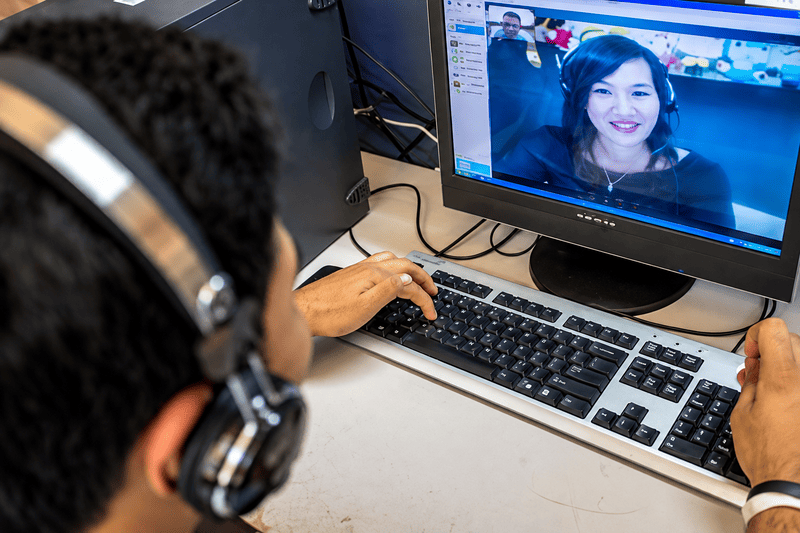 Seseorang menggunakan headset saat berkomunikasi melalui panggilan video di komputer.