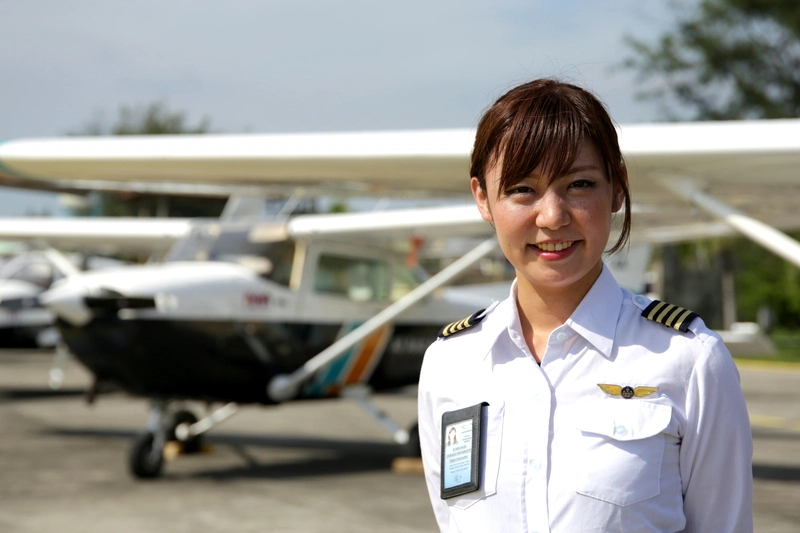 Instruktur penerbangan perempuan AAA Academy mengenakan seragam pilot di depan pesawat latih.